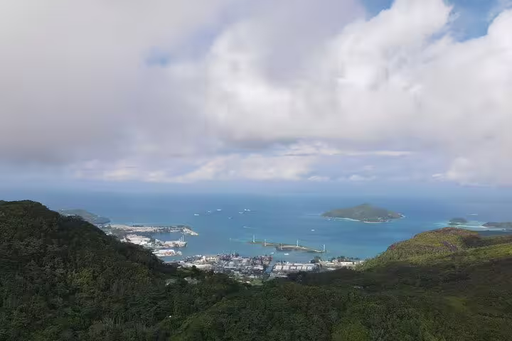 Aerial view of Seychelles harbor and lush green hills under a cloudy sky, perfect for a private island tour.