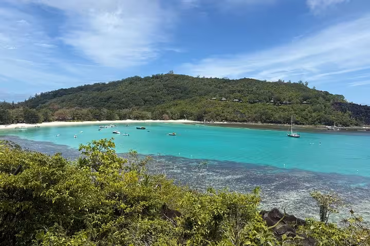 Stunning turquoise bay with boats in Seychelles, perfect for relaxing transfer tours and beach exploration.
