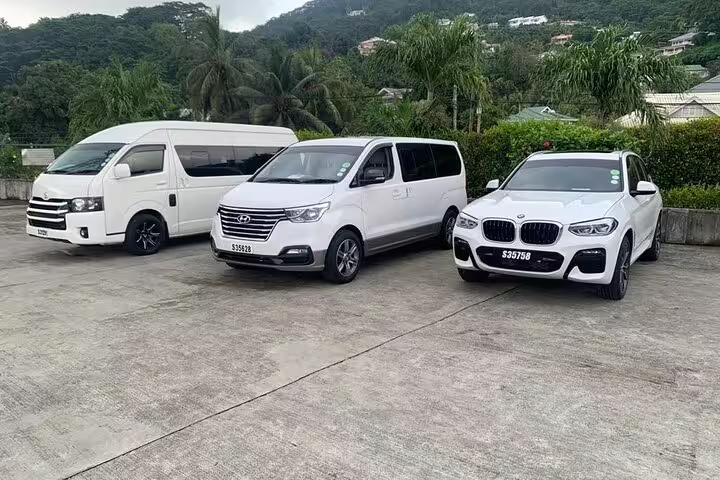 Luxury fleet of vans and cars for Seychelles VIP Transport Services, offering premium travel options amid tropical scenery.