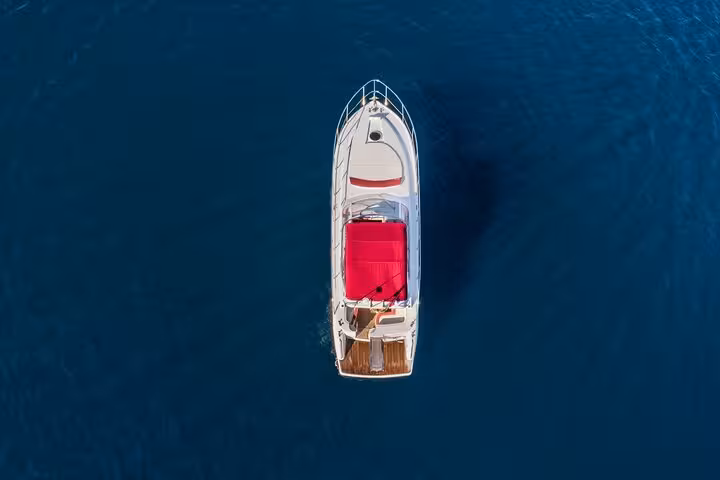 Aerial view of the sleek Shamal 40 boat with a vibrant red canopy cruising the deep blue waters of Amalfi Coast.