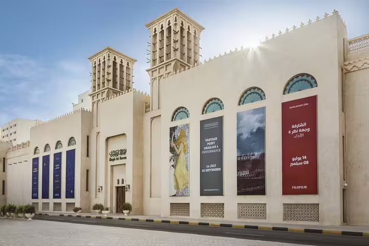 The exterior of a cultural museum in Sharjah, showcasing vibrant banners on a Full-Day Six Emirates Tour.