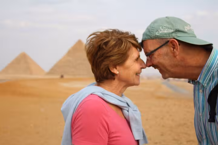 Couple posing by the Giza Pyramids during Sharm to Cairo flight tour, pyramids visible in the desert