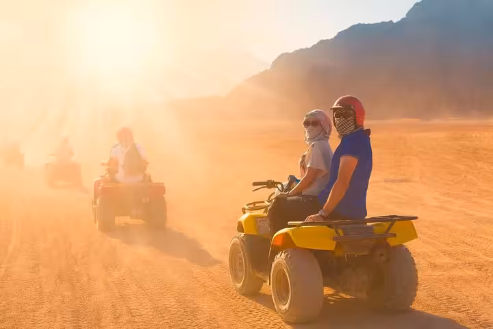 Couple on yellow quad bike in Sharm El Sheikh at sunrise, desert ATV safari with mountains and dust