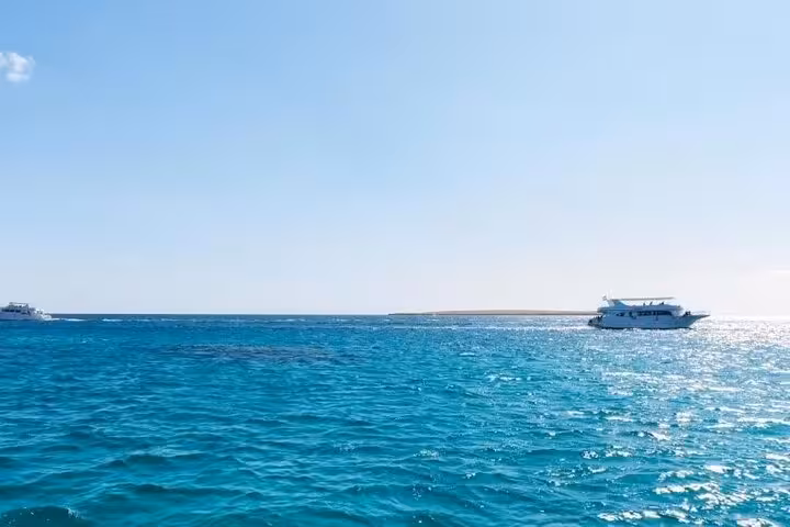 Crystal-clear Red Sea near Sharm El Sheikh with dive boat offshore, beach diving trip with hotel transfer