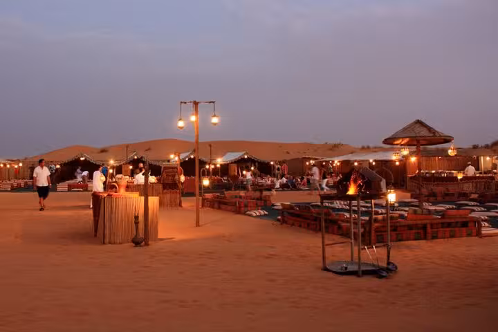 Bedouin desert camp dinner show in Sharm El Sheikh with lanterns, seating and fire at sunset