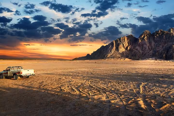 Sharm El Sheikh desert safari sunset with mountain backdrop and 4x4 pickup, ideal for stargazing tour
