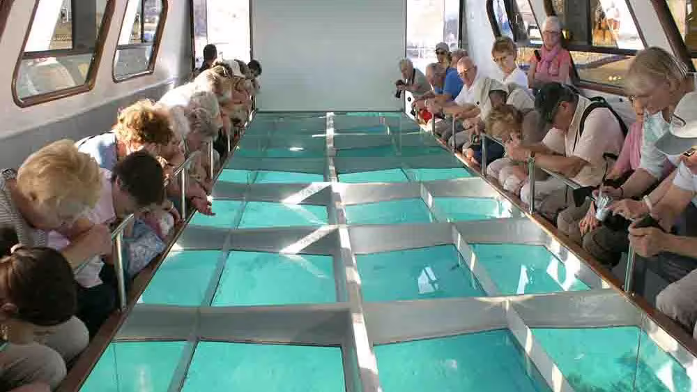 Tourists viewing Red Sea reefs through glass-bottom boat on a Sharm El Sheikh water sports day tour