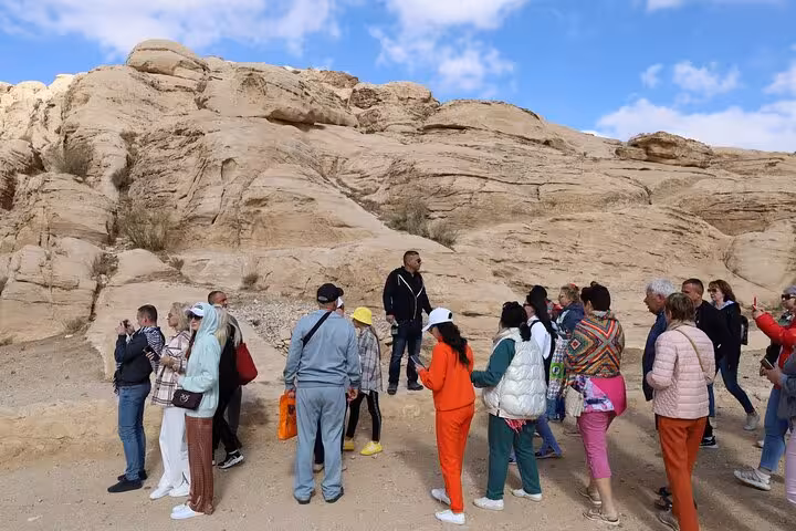 Tour group exploring desert rock formations on Sharm El Sheikh to Petra day tour by ferry in Jordan