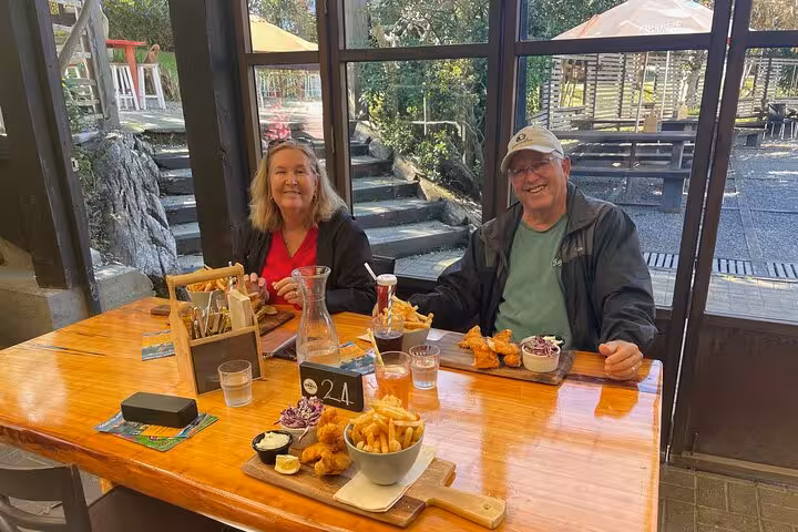 Couple enjoying a delightful meal inside a cozy restaurant during the Sheep World Country Tour from Auckland.