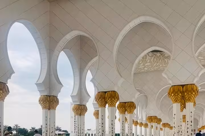 Sheikh Zayed Grand Mosque colonnade with white arches and gold capitals on a private Abu Dhabi city tour