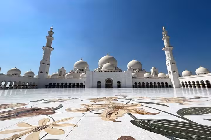 Daytime wide view of Sheikh Zayed Grand Mosque domes and marble courtyard on Abu Dhabi guided visit