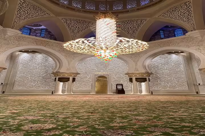Sheikh Zayed Grand Mosque prayer hall interior with massive chandelier and patterned carpet on sunset visit