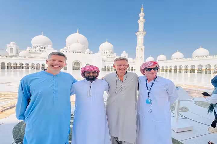 Tour guests with local guide posing at Sheikh Zayed Grand Mosque Abu Dhabi, ideal for sunset visit option