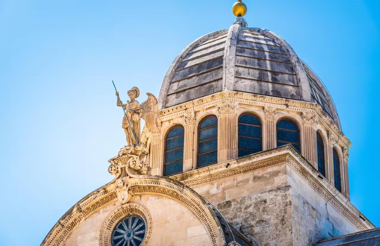 Šibenik Cathedral dome and angel statue against blue sky, Dalmatian coast highlight on Croatia self-drive tour