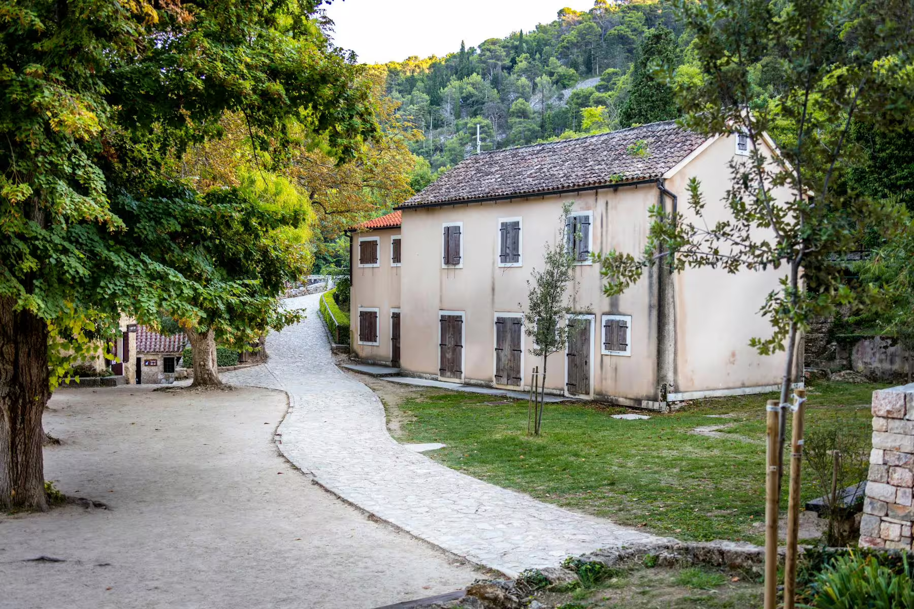 Traditional stone houses and shaded path near Krka National Park, seen on the Šibenik and Krka day tour from Zadar
