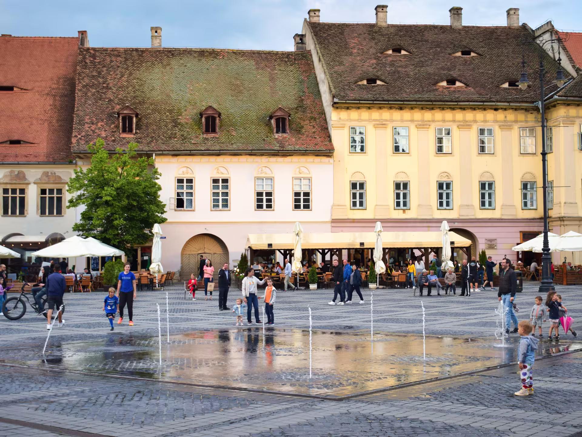Lively Grand Square of Sibiu with fountains and colorful Saxon buildings on a Cluj-Napoca day tour