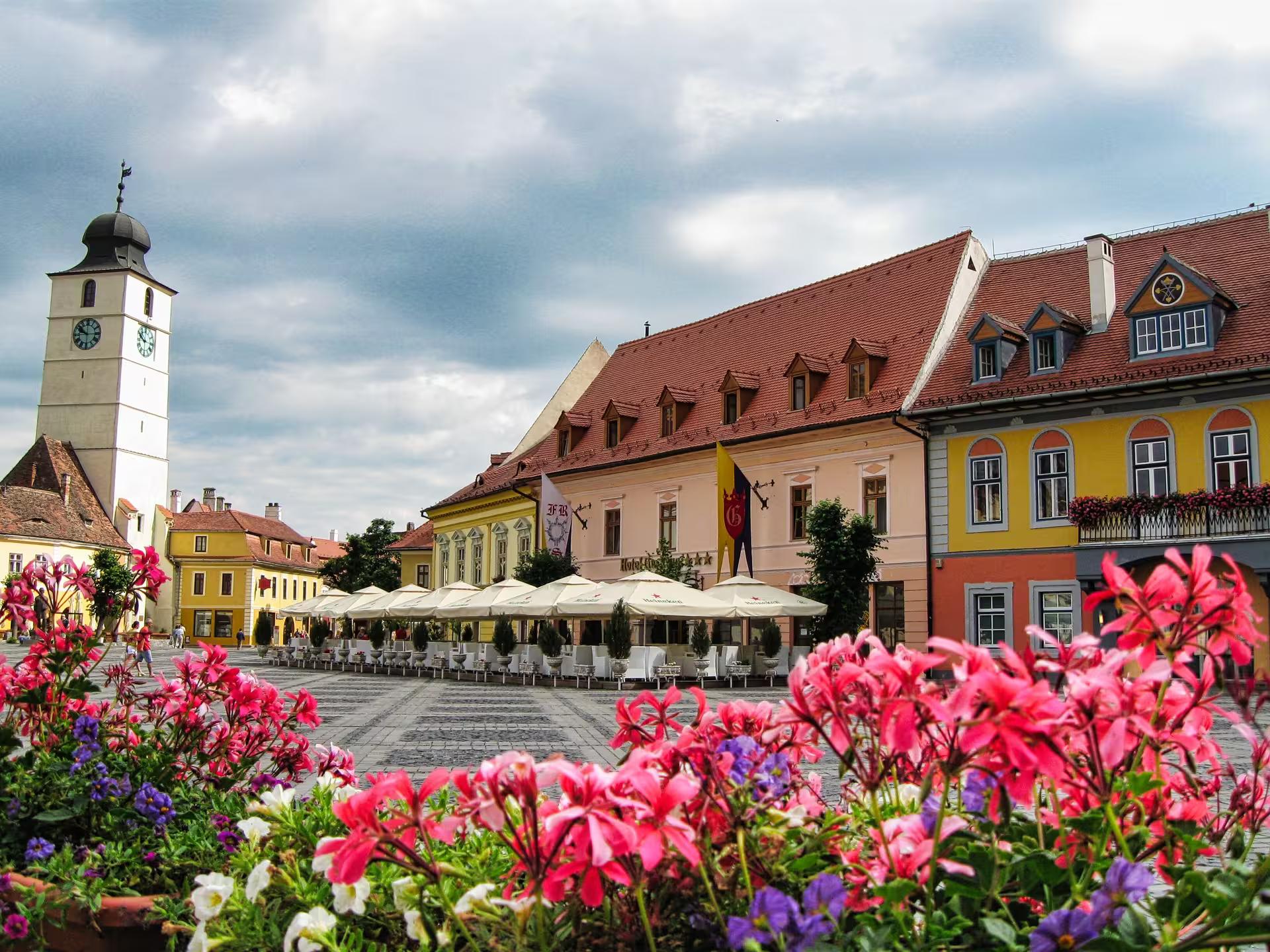 Colorful Sibiu Large Square with clock tower and blooming flowers on a scenic day trip from Cluj-Napoca Romania