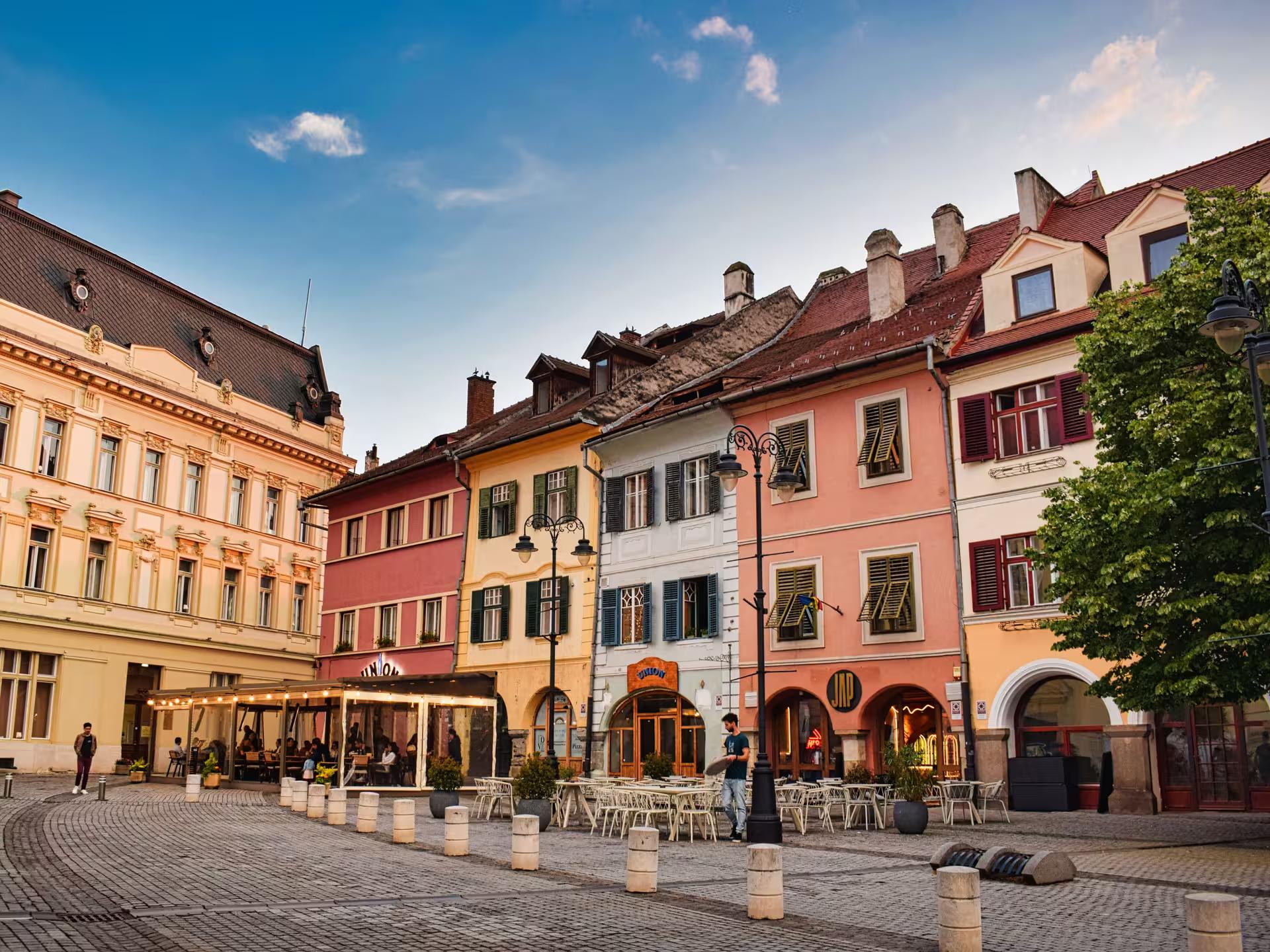Colorful historic buildings and outdoor cafes in Sibiu old town square visited on a day trip from Cluj-Napoca