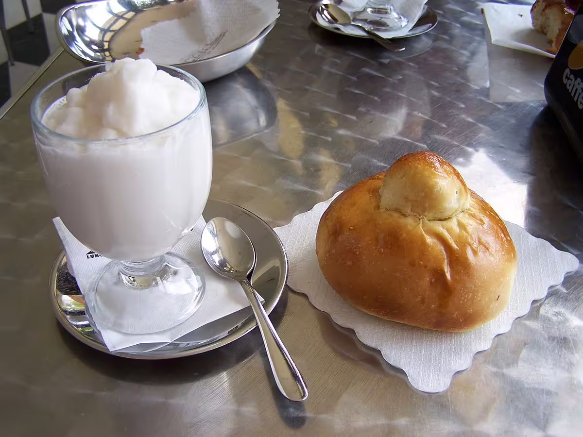 Traditional Sicilian brioche with refreshing lemon granita served at a café, tasting local flavors on a Calabria holiday