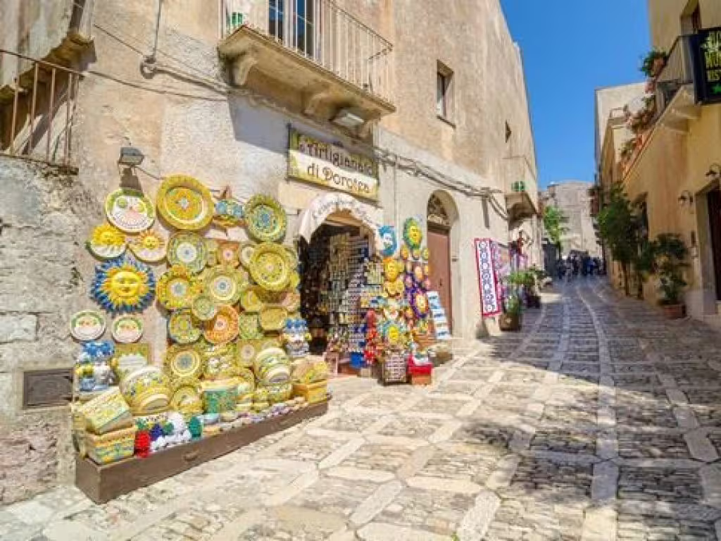 Colorful Sicilian ceramics displayed along a cobbled street in medieval Erice village on a private tour from Palermo