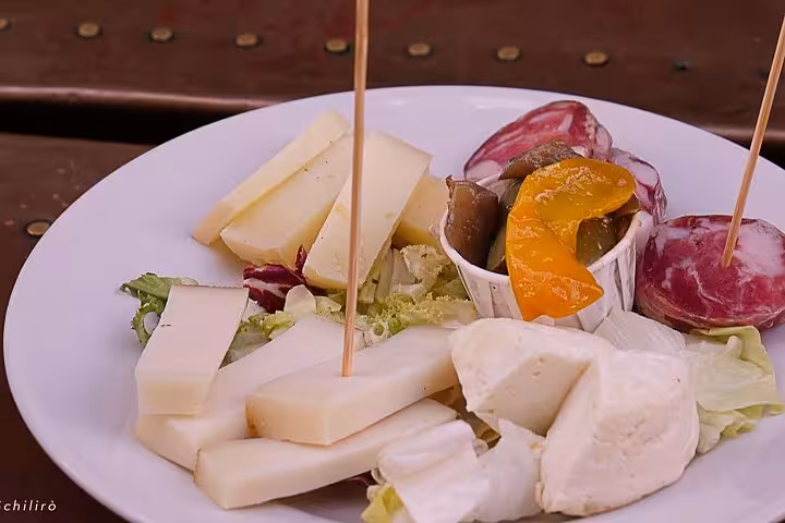 Plate of assorted Sicilian cheeses and vegetables at a Catania street food tour, showcasing local culinary delights.