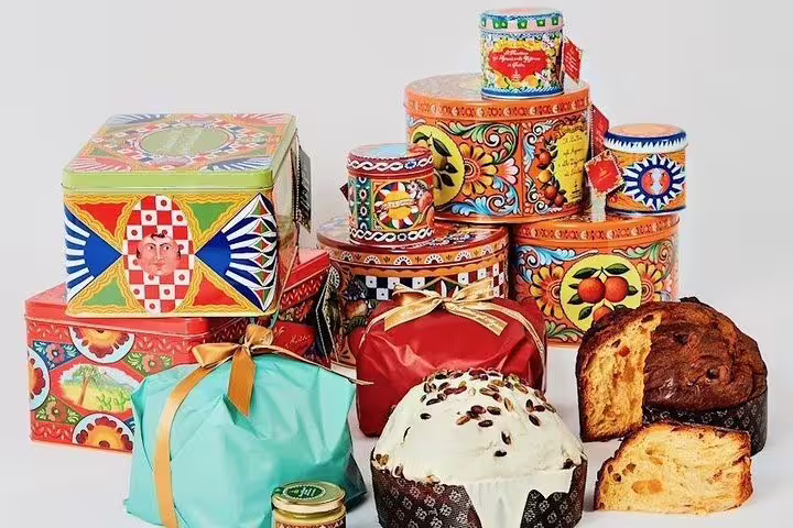 Colorful Sicilian pastries and panettone in decorative tins and gift boxes from Castelbuono and Cefalù on private Palermo tour
