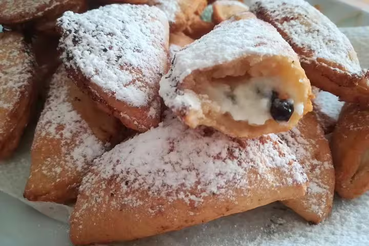 Traditional Sicilian pastries filled with ricotta and chocolate, dusted with sugar on a Scopello private food tour