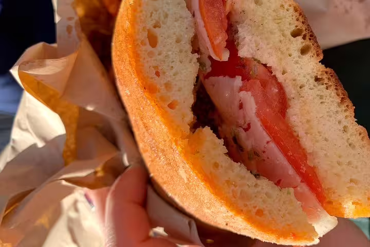 Traditional Sicilian sandwich with fresh tomato and cured meat enjoyed on a Scopello private tour from Palermo