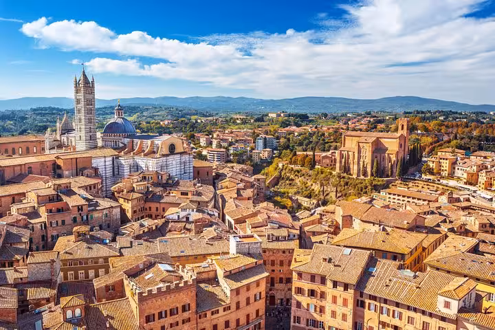 Aerial view of Siena's historic architecture under a vibrant sky, part of a Tuscany tour from Florence.
