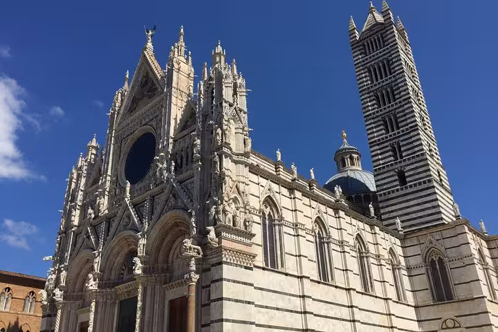 Stunning view of the Siena Cathedral’s intricate facade and bell tower under a clear blue sky.