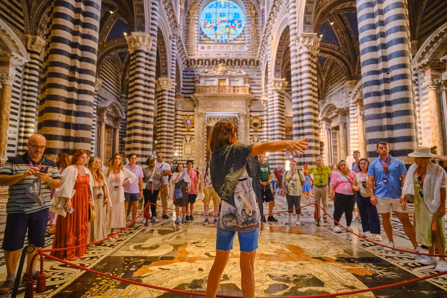 Tour guide leading a group inside the stunning Siena Cathedral, showcasing its iconic striped columns and ornate interior.