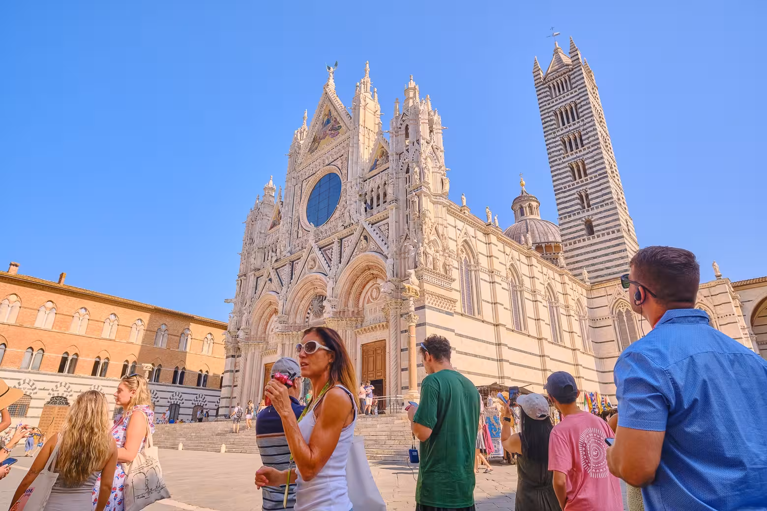 A group of tourists admires the stunning facade of Siena Cathedral during a day trip in Tuscany.