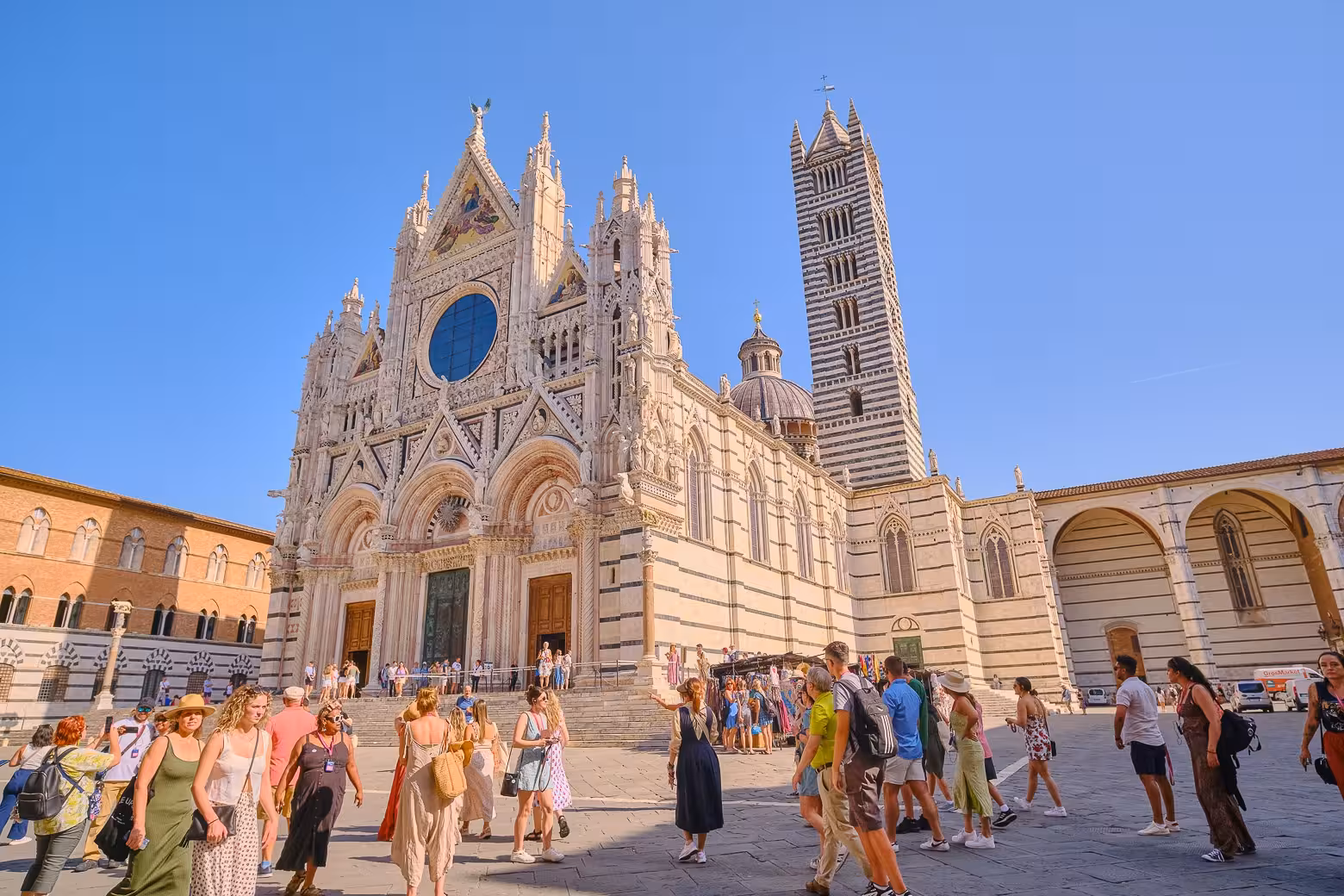 Tourists admiring the stunning facade of Siena Cathedral on a Tuscany guided tour.