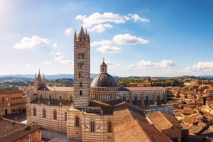 Stunning view of the Siena Cathedral's intricate architecture under a clear blue sky in Tuscany, Italy.