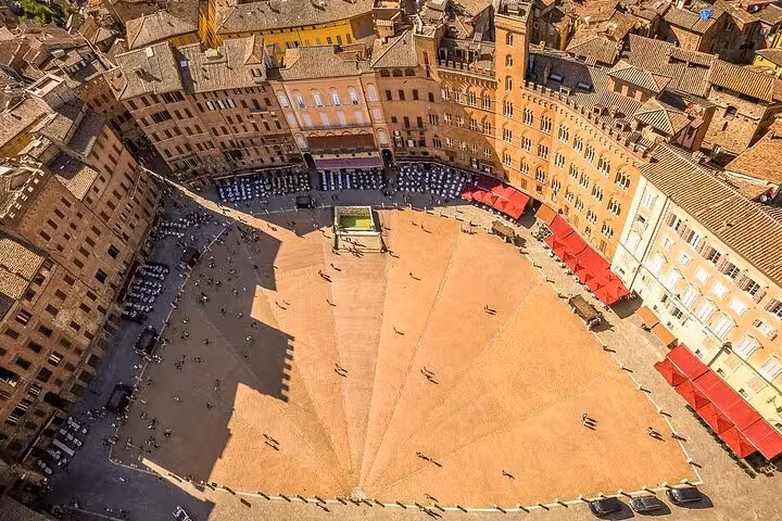 Aerial view of Siena's Piazza del Campo, showcasing its unique shell shape and medieval architecture in Tuscany.
