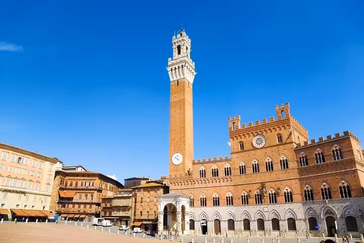 Historic Piazza del Campo in Siena featuring the iconic Torre del Mangia under a clear blue sky on Livorno port excursion.