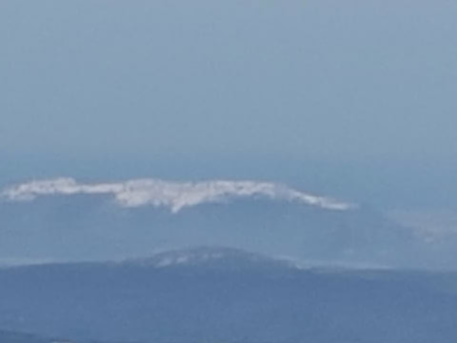 Distant view of snow-capped Sierra Bermeja mountains under clear blue sky, perfect for private hiking adventure.