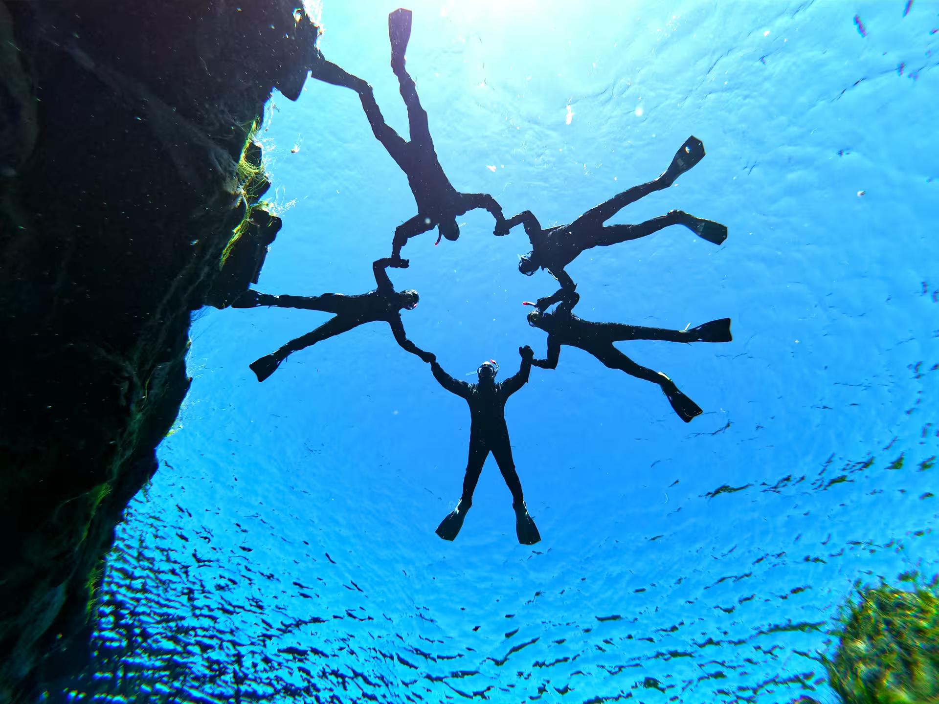 Snorkelers form a circle in the crystal-clear waters of Silfra, Iceland, showcasing the unique Cold & Hot snorkeling adventure.