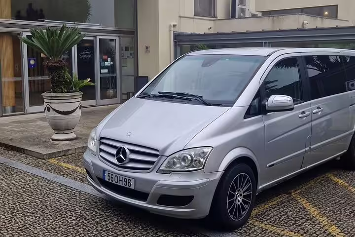 Silver Mercedes van parked outside a hotel, ready for private transfer between Porto and Lisbon for a smooth ride.