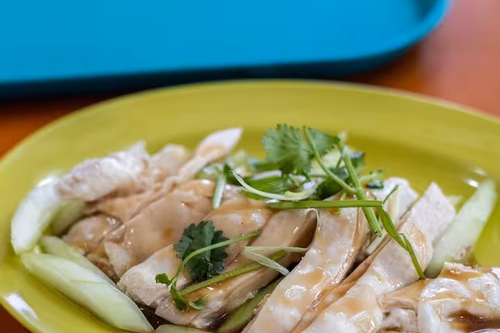 Tender poached chicken with fragrant herbs on a vibrant plate, featured in Singapore Chinatown Hawker Food Tour.