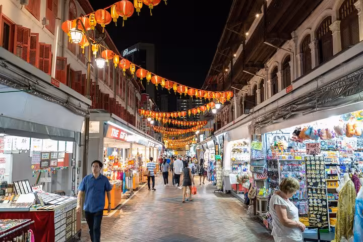 Vibrant Singapore street market at night with red lanterns and bustling shops in Chinatown.