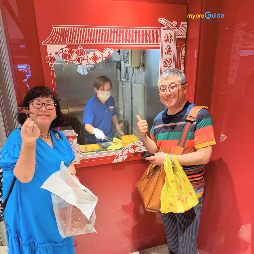 Tourists enjoying local treats at a bustling Chinatown vendor during a Singapore walking tour.