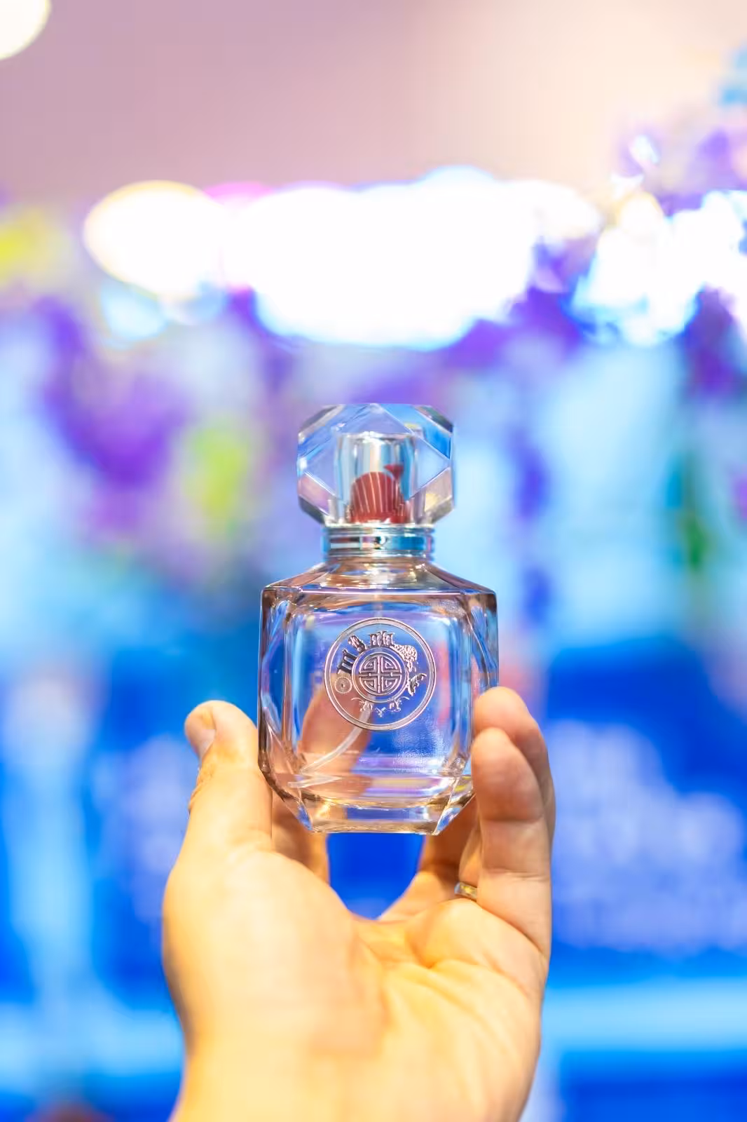 Crystal perfume bottle held against vibrant backdrop, part of Singapore Little India Spice Discovery and Perfume Workshop.
