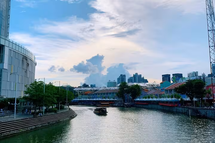 Scenic daytime view of Singapore River with boats and colorful buildings, highlighting the city's vibrant urban landscape.