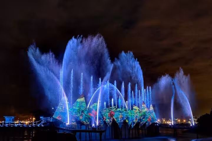 Stunning night view of Singapore's light and water show during the Night Extravaganza Cruise with vibrant displays.