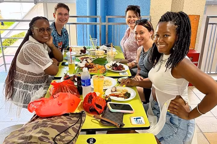 Group of friends enjoying diverse Singaporean street food at a colorful hawker center table, capturing cultural experience.