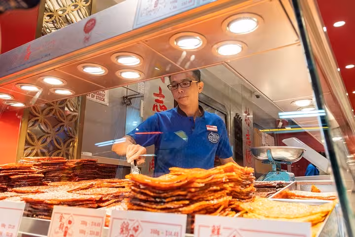 Vendor serving freshly grilled meat at a popular snack stall, highlighting Singapore's rich culinary traditions.