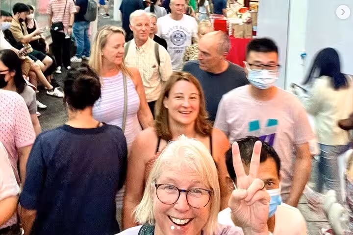 Excited visitors explore a lively Singapore street market, capturing the essence of the UNESCO cultural experience tour.