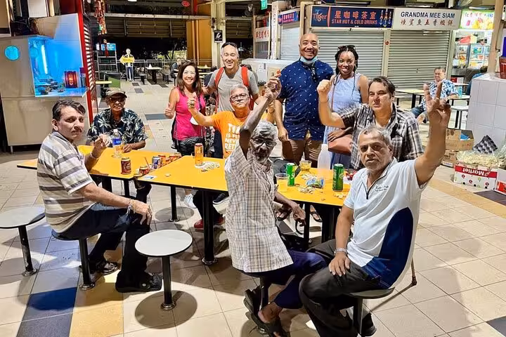 A diverse group of people celebrating at a bustling Singaporean food court, showcasing cultural unity through cuisine.