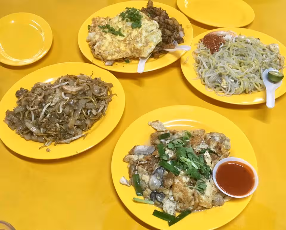 Assorted Singaporean street food dishes on colorful plates, highlighting the UNESCO food tour experience.
